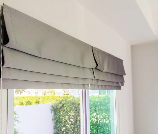 Graues Raffrollo am Fenster, dekorativ gefaltet