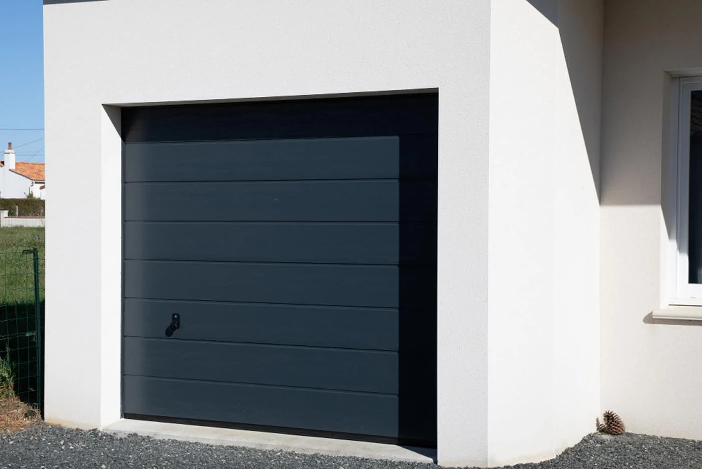 Graues Garagentor an einem modernen Einfamilienhaus – Beispiel für einen nachgerüsteten Rollladen, der manuell oder elektrisch bedient werden kann.